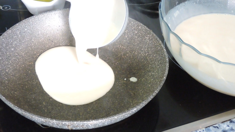 Añadiendo la masa de crepes a la sartén caliente