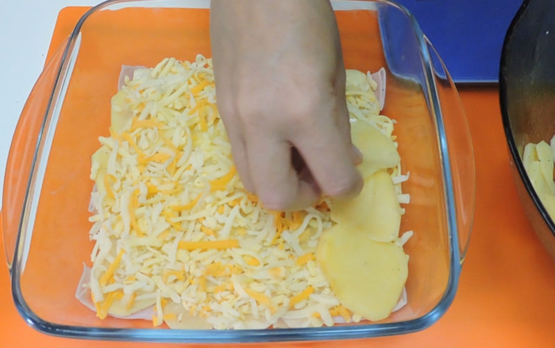 Colocando una capa de patata sobre el queso