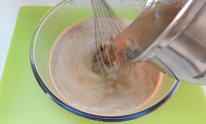 Vertiendo la leche con chocolate en la mezcla de yemas
