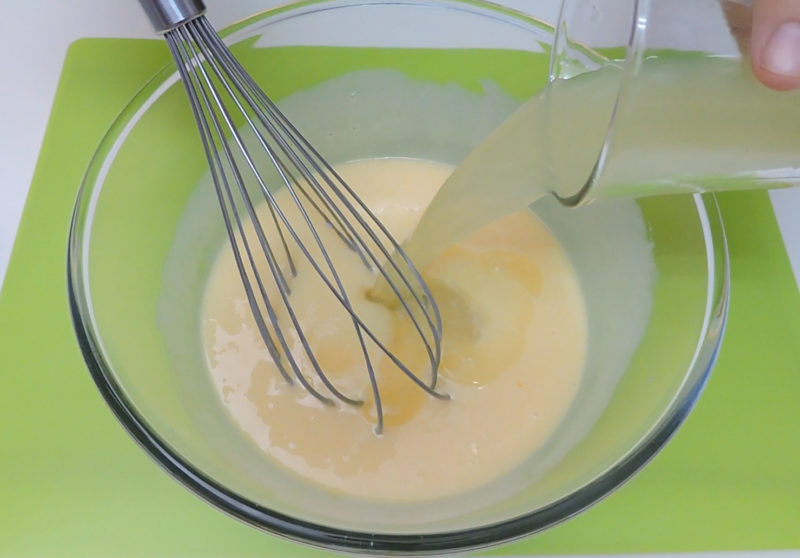 Vertiendo el zumo de limón en la mezcla de yemas y leche condensada