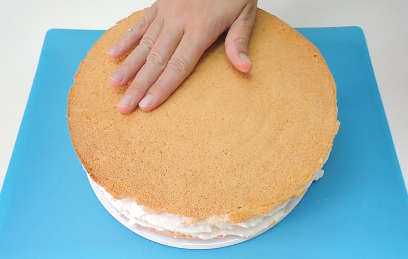 Colocando el tercer bizcocho en la superficie de la tarta