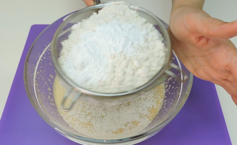 Tamizando la harina y la levadura química sobre la mezcla de huevos, azúcar, aceite y leche