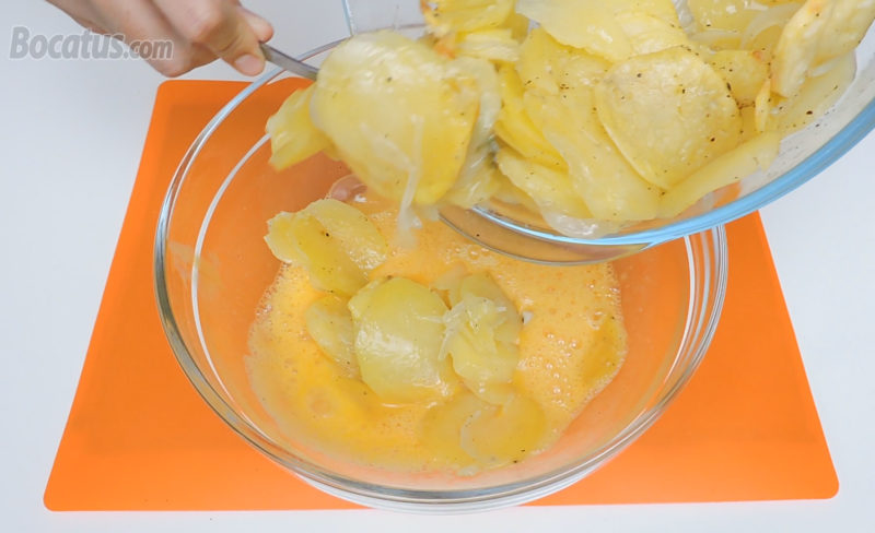 Añadiendo las patatas y cebolla a los huevos batidos