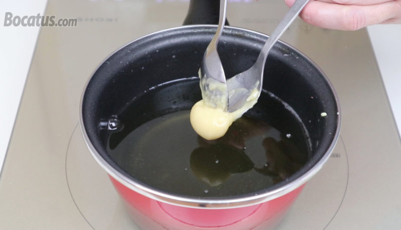 Añadiendo la masa de buñuelos en el aceite