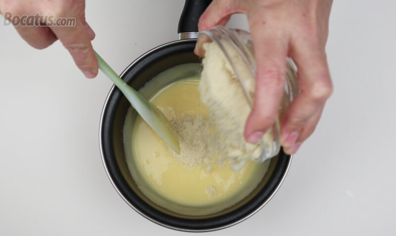 Añadiendo la almendra molida a la mezcla de yemas y leche condensada